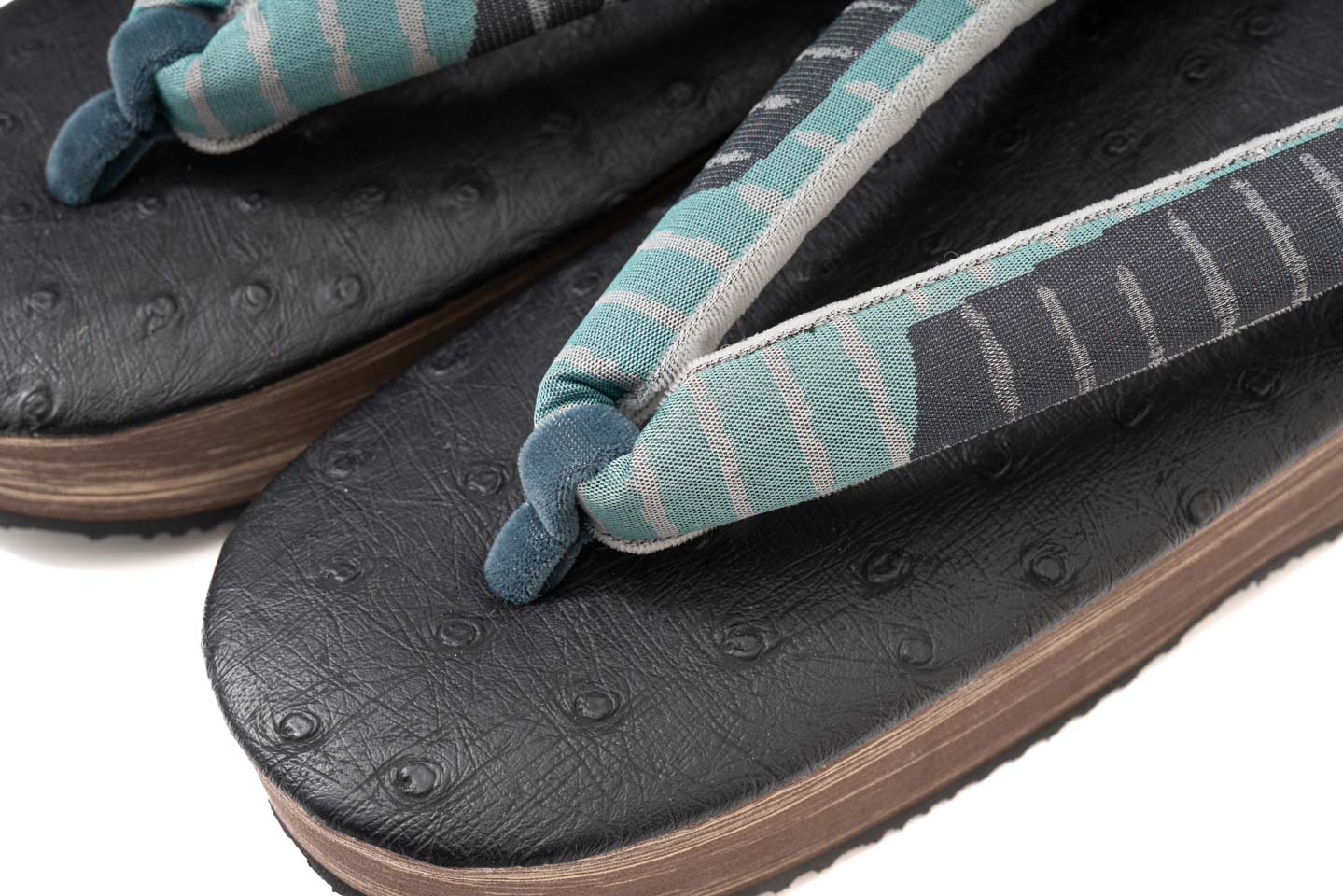 青緑の花緒をつま先側から捉えたディテールである 草履台の天の質感もよくわかる